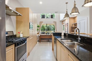 Una cocina moderna con una isla central, electrodomésticos de acero inoxidable e iluminación colgante.