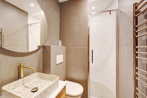 Ein modernes Badezimmer mit einem freistehenden Waschbecken, einer Toilette und einer Duschkabine.