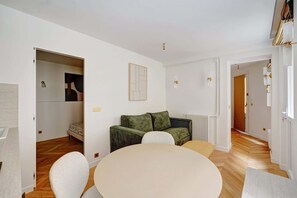 Ein modernes Wohnzimmer mit rundem Tisch, einer Couch und einem Essbereich.
