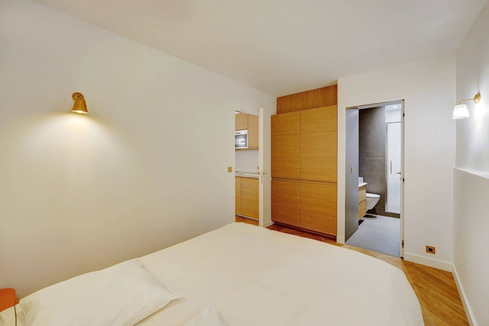 A bedroom with a bed, a wardrobe, and a bathroom visible through an open door.