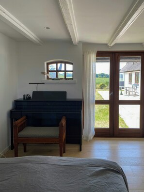 Ein Zimmer mit einem Bett, einem Schreibtisch mit Stuhl, einem Fenster mit Vorhängen und Blick nach draußen.