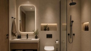 Un baño moderno con ducha envuelta en vidrio, tocador con espejo y un inodoro.