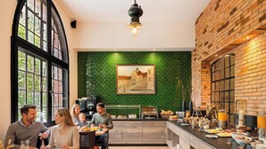 Un comedor con pared de ladrillo, salpicadero de azulejos verdes y una cafetera.