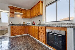 Une cuisine avec des meubles de rangement en bois, un four à micro-ondes et une cuisinière.