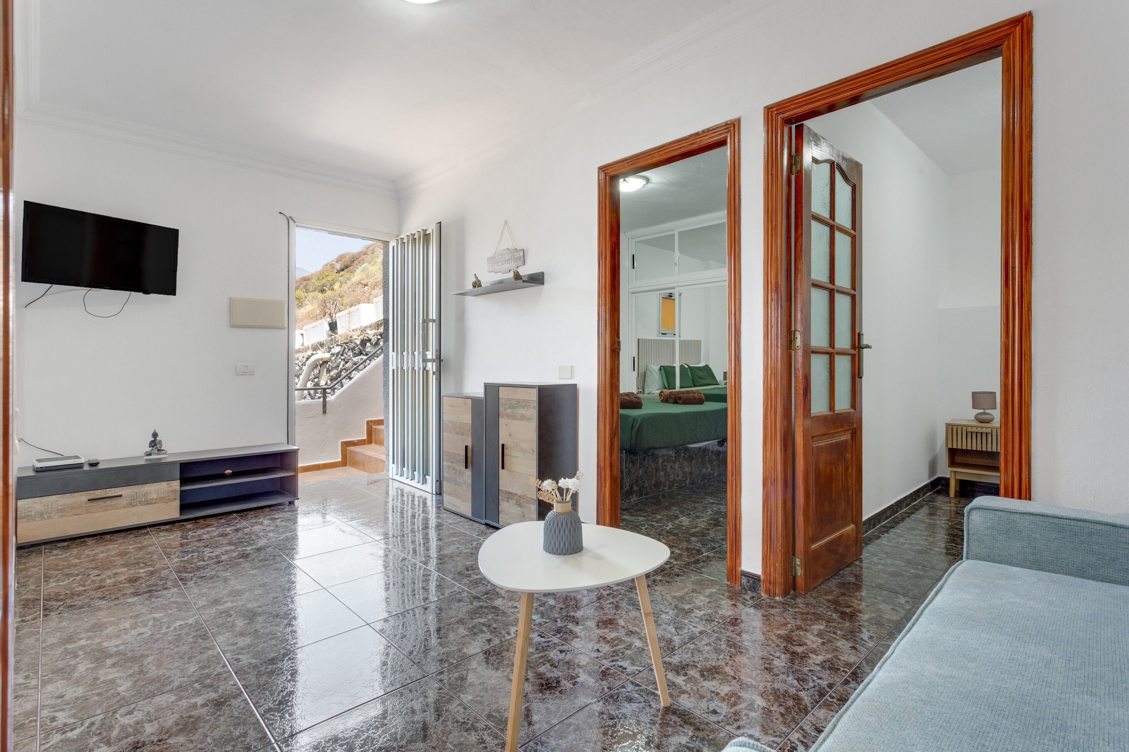 Een moderne woonkamer met een flatscreen televisie, een bank, een salontafel en een trap naar een balkon.