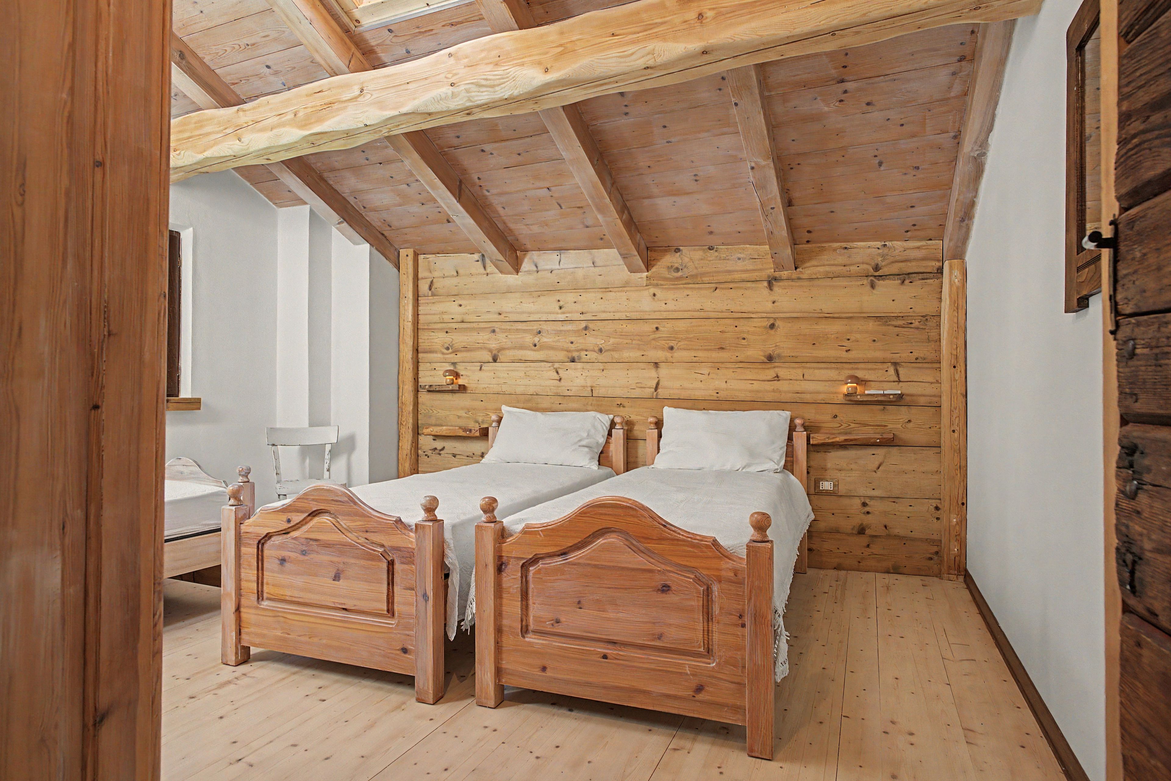 Een slaapkamer met twee houten bedden, een houten plafond en een witte muur.