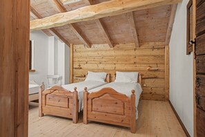 Un dormitorio con dos camas de madera, techo de madera y pared blanca.