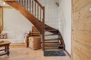 A wooden staircase with a wooden cabinet and a sofa in a room with tiled flooring.