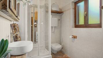 Une salle de bain avec un lavabo blanc, des toilettes et un espace douche.