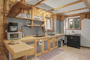 Una cocina rústica con vigas de madera, un lavamanos, una estufa y un microondas.