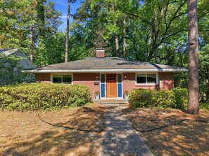 A single-story brick house with a front porch, a chimney, and a well-maintained lawn.