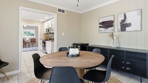 Una cucina moderna con zona pranzo, che include un tavolo rotondo in legno, sedie nere e un piano di lavoro nero con un forno a microonde.