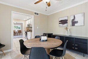 A modern kitchen with a dining area, featuring a round wooden table, black chairs, and a black countertop with a microwave. - Offering the perfect balance of quiet neighborhood living and urban convenience. (Durham)