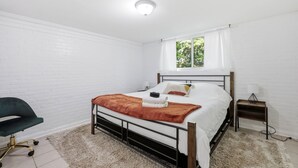 Una camera da letto con un letto, una sedia, un comodino e una finestra.