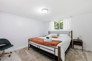 A bedroom with a bed, a chair, a bedside table, and a window. - Offering the perfect balance of quiet neighborhood living and urban convenience. (Durham)
