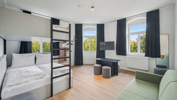 Ein modernes Schlafzimmer mit Etagenbett, Schreibtisch, Sofa und großen Fenstern.