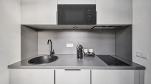Una cocina moderna con microondas integrado, un lavamanos y una cafetera.