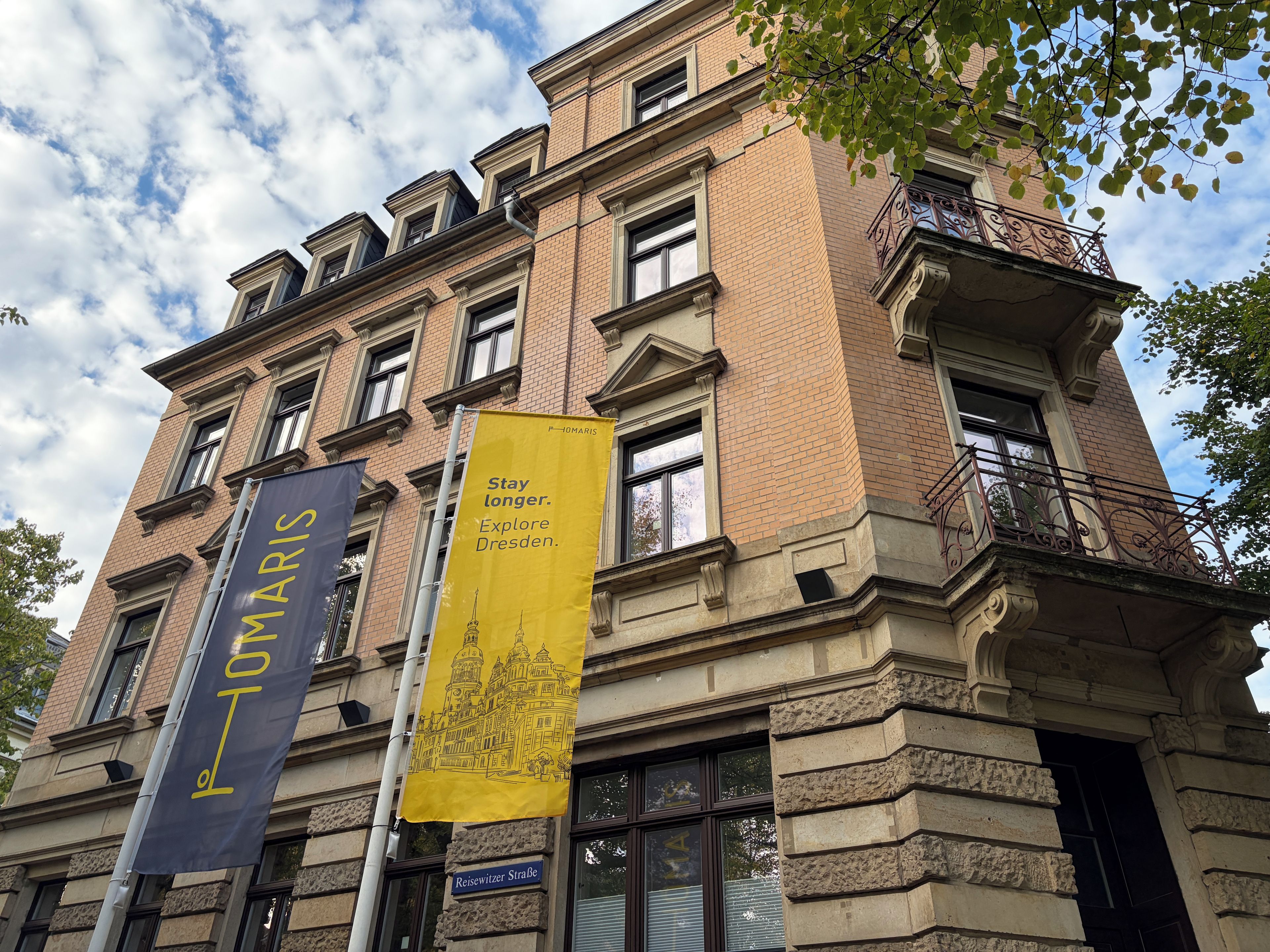 Ein Gebäude mit Ziegelverkleidung, zahlreichen Fenstern und zwei Bannern, die den Tourismus bewerben.