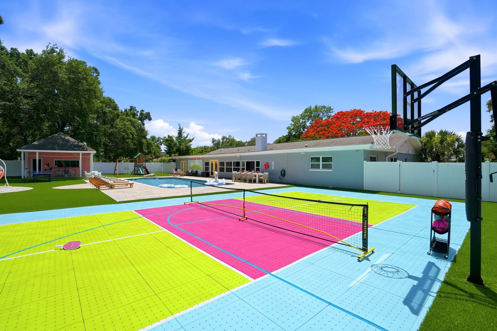 A multi-sport court with a basketball hoop, a tennis net, and a volleyball net.