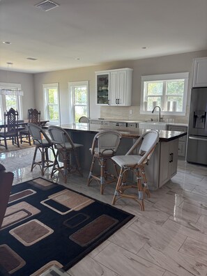 A modern kitchen with a central island, bar stools, and a dining area with a chandelier. -     Luxury Waterfront Retreat Private Dock, Boat Lift & Stunning Bay View (Freeport)