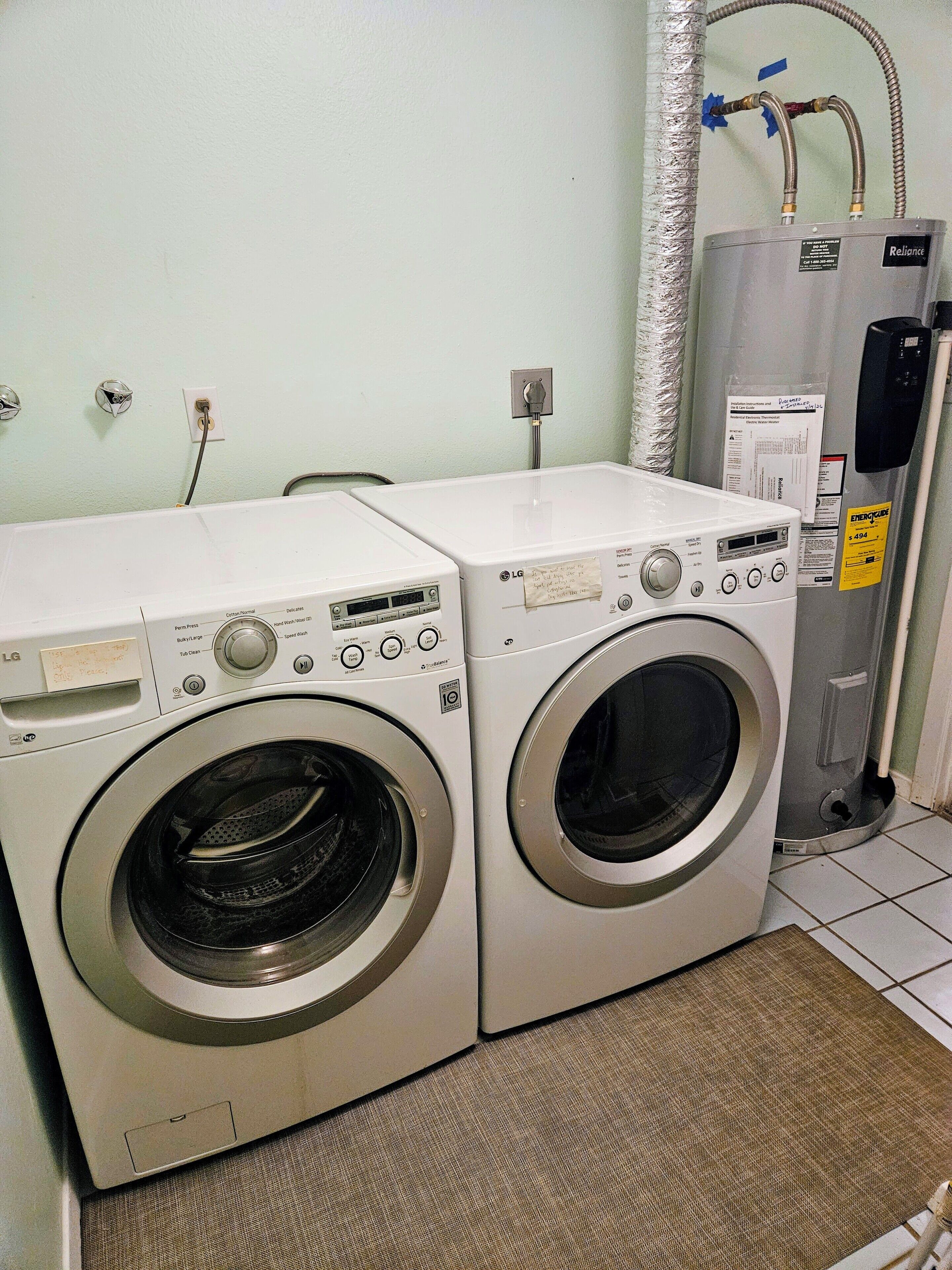 A laundry room with two front-loading washing machines and a water heater.