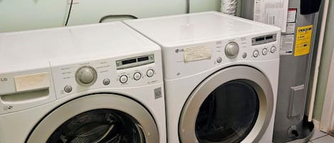A laundry room with two front-loading washing machines and a water heater.