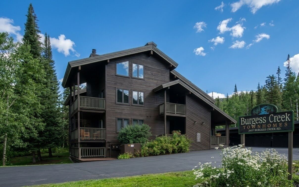 A two-story building with a balcony, surrounded by trees and a clear sky.