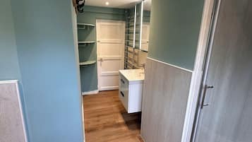A hallway with a wooden floor, a white door, and a shower area.