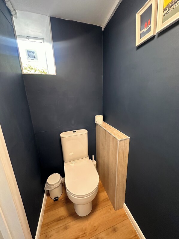 Un baño pequeño con inodoro, un mueble de madera y una ventana.