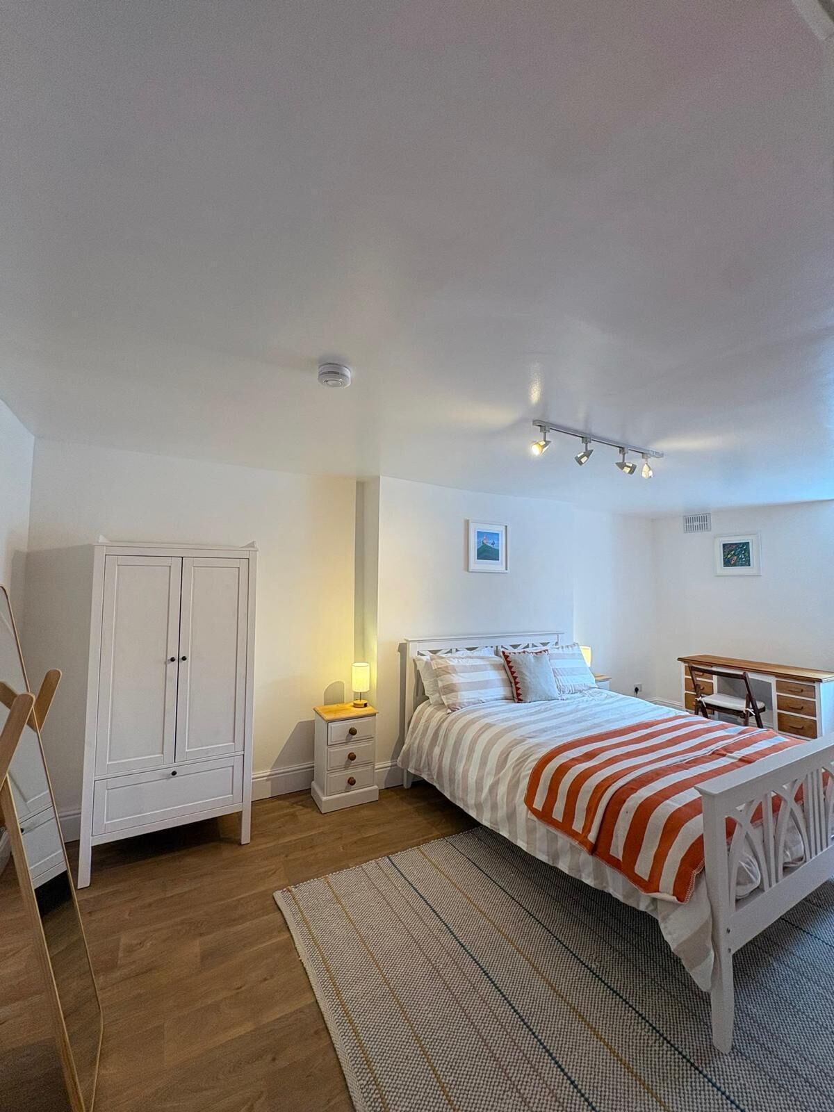 A bedroom with a bed, a wardrobe, a desk, and a chair.