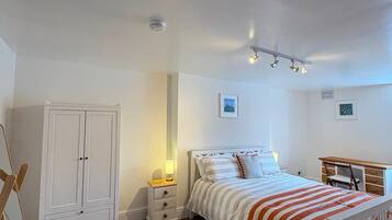 A bedroom with a bed, a wardrobe, a desk, and a chair.