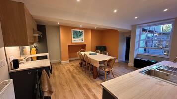 A modern kitchen with wooden cabinets, a dining table with chairs, and a large window providing natural light.