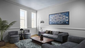 Ein modernes Wohnzimmer mit einer grauen Sofagarnitur, einem Couchtisch, einer Stehlampe und einem großen Blumenbild an der Wand.