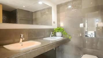 A modern bathroom with a dual sink vanity, a toilet, and a large mirror.