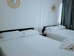 Ein Hotelzimmer mit zwei Betten, weißer Bettwäsche, einem Nachttisch mit Lampe und einem Wandbild.