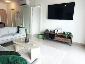 Ein modernes Wohnzimmer mit einer Couch, einem Couchtisch und einem an der Wand befestigten Fernseher.