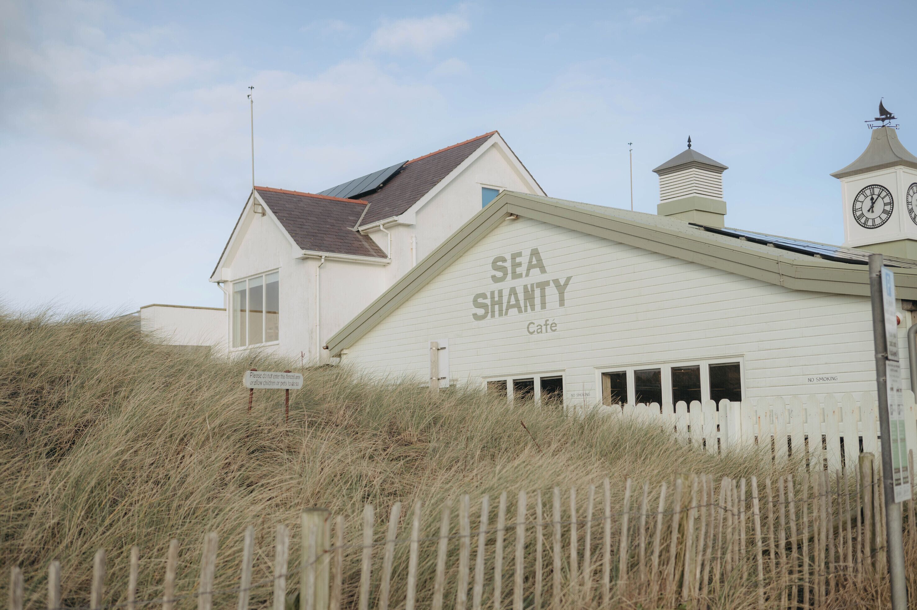 A building with a sign reading 'SEA SHANTY Café' and a clock tower.
