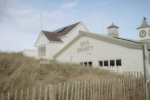 A building with a sign reading 'SEA SHANTY Café' and a clock tower. - Beach Court by Guestz (Trearddur Bay)