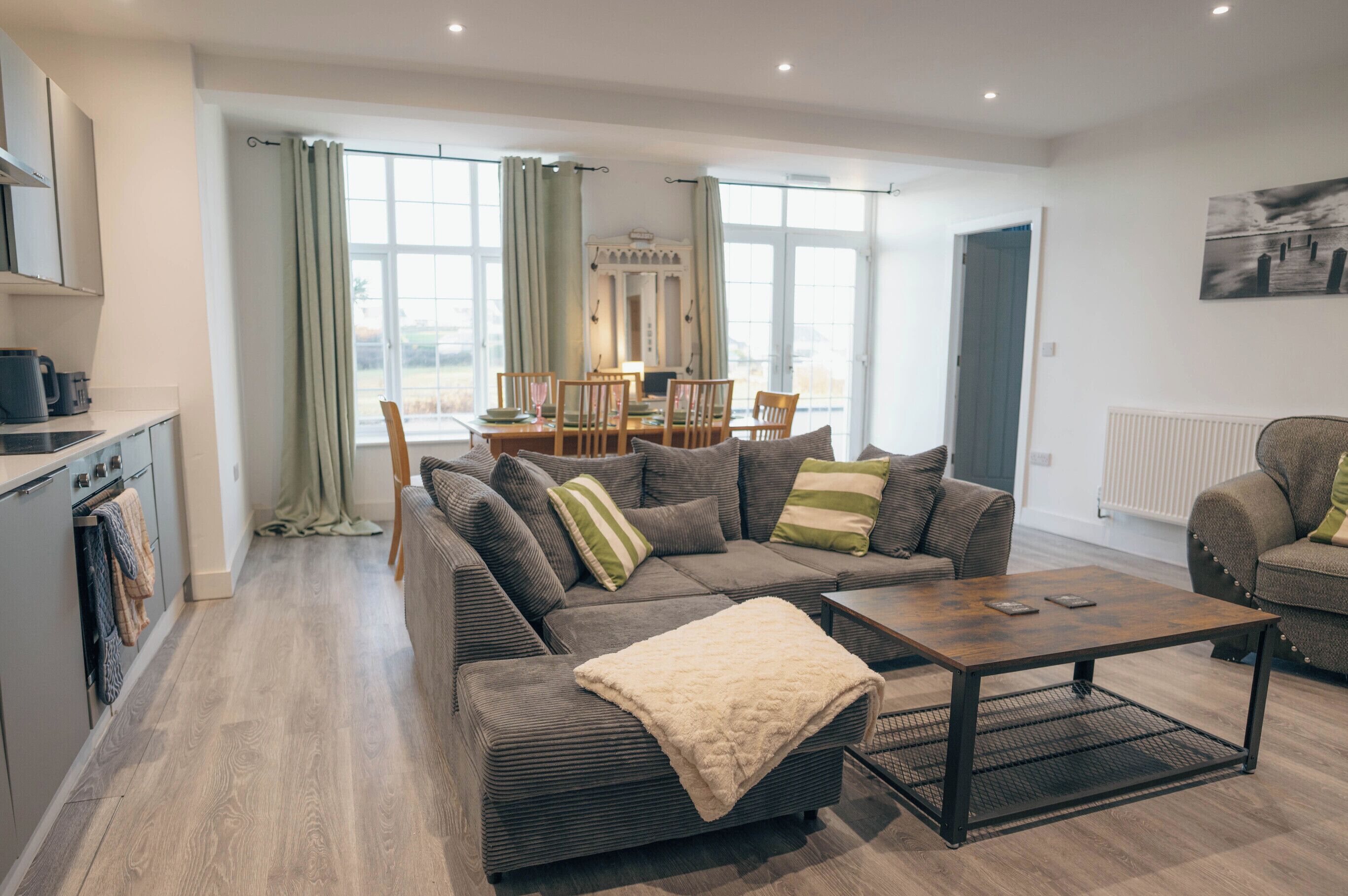 A modern living room with a sofa set, a coffee table, and a dining area with chairs and a table.