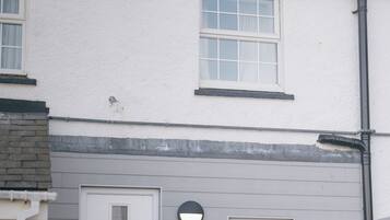 A residential building with a white exterior, a front door, a small window, and a bench.