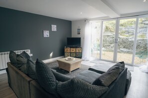 Un salon moderne avec un canapé, un téléviseur et un meuble.