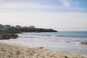 A coastal beach with a row of white houses on a rocky outcrop. - Beach Court by Guestz (Trearddur Bay)