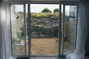 A sliding glass door leading to a gravel patio with a rock wall and a wooden fence.