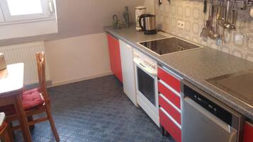 A kitchen with a red and white color scheme, a stove, a dishwasher, and a coffee maker.
