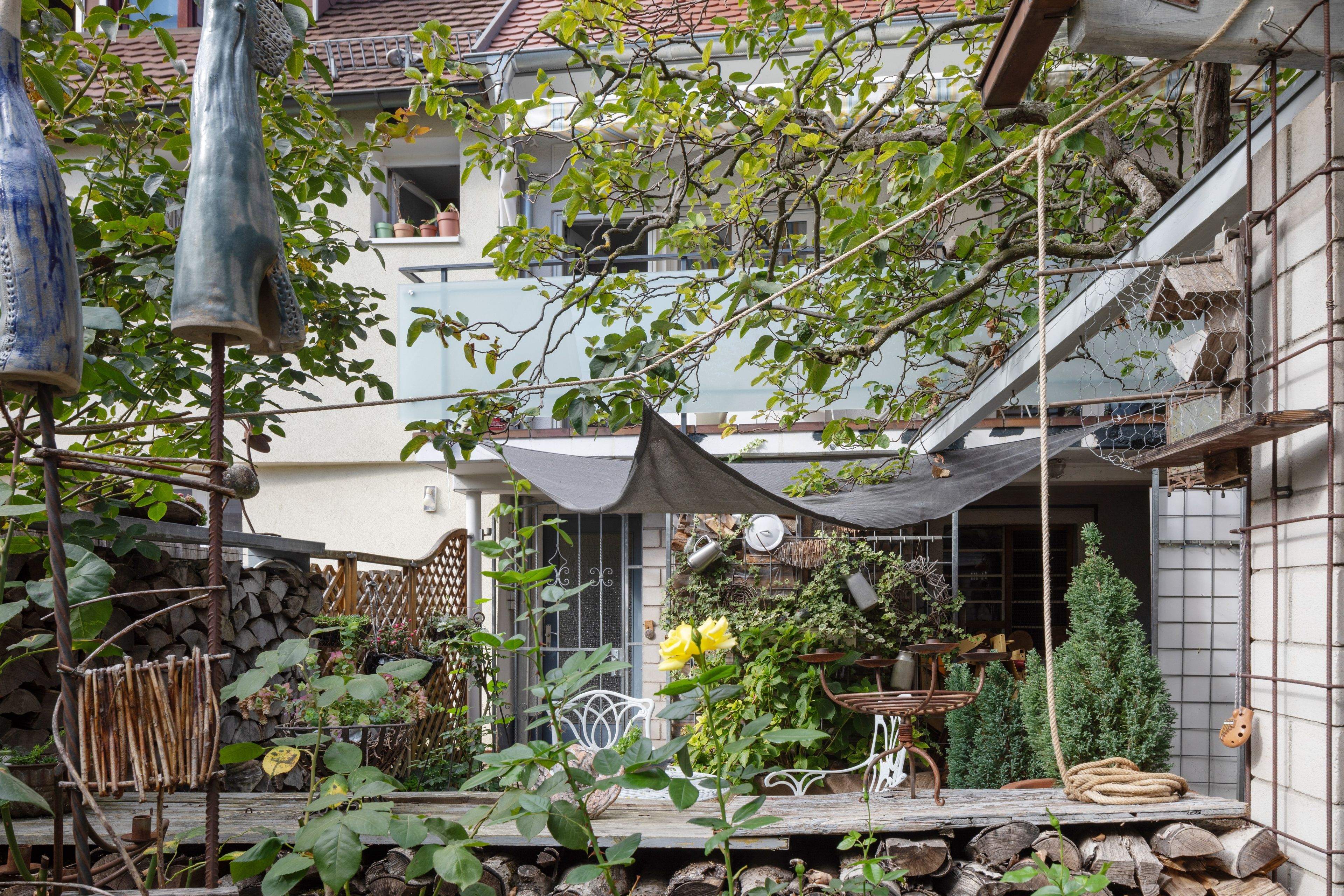 Un patio con una mesa de madera, sillas y una variedad de plantas en macetas.