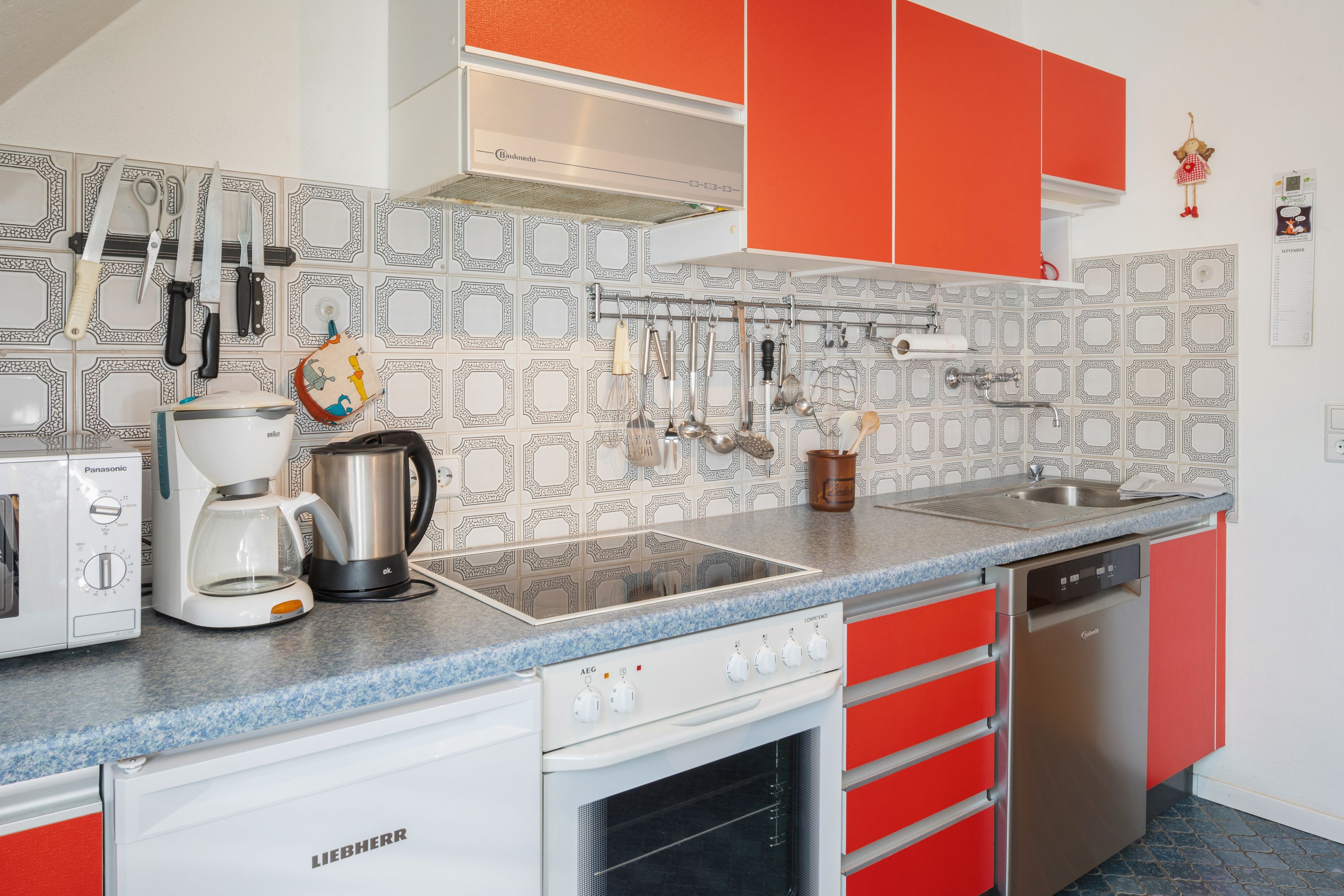 Uma cozinha moderna com cafeteira, chaleira e diversos utensílios sobre o balcão.