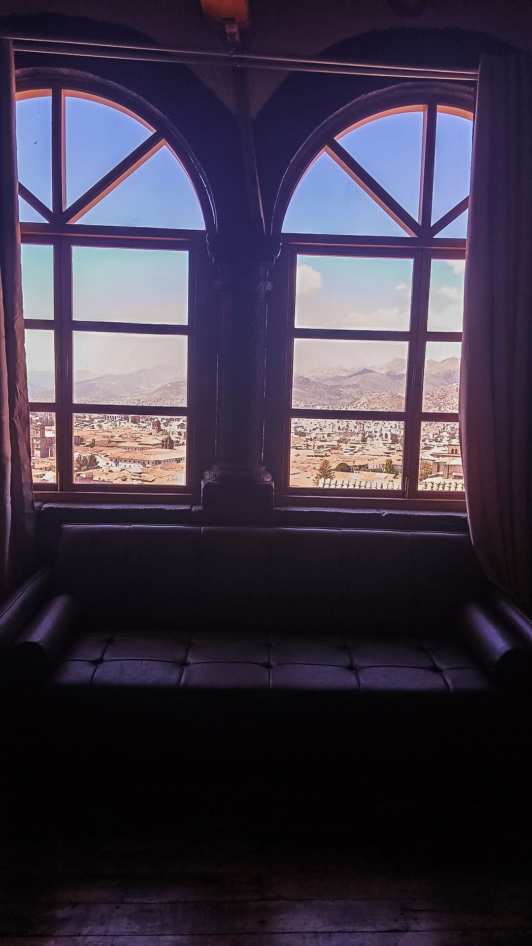A room with a large arched window overlooking a cityscape.