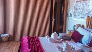 Un dormitorio con cama de madera, una manta roja y suelo de madera.