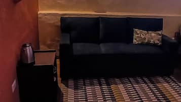 Una habitación con un sofá, un tapete estampado, una mesita y un espejo colgado en la pared.