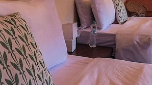 Ett hotellrum med två sängar, en sänggavel i trä och ett litet bord med en flaska på.